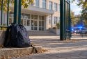 Илюстративно изображение на ученическа раница пред училище, създадено с изкуствен интелект
